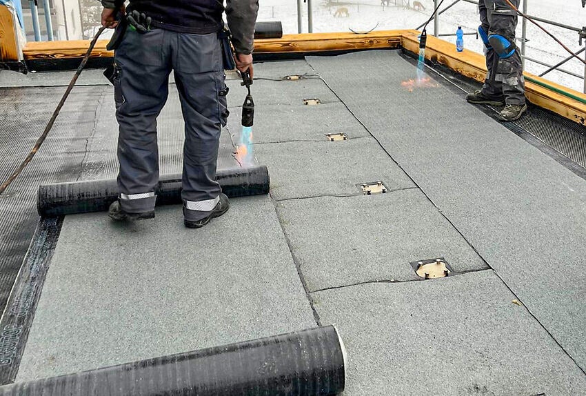 Arbeiter auf Dachterrasse beim Abdichten